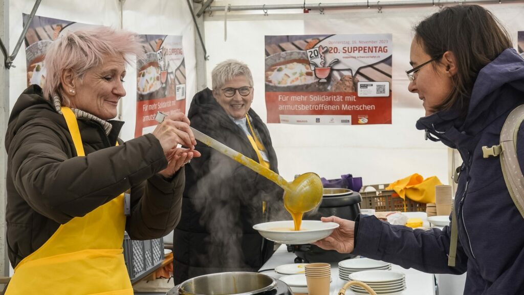 Une image d'un bénévole distribuant de la soupe à une personne.