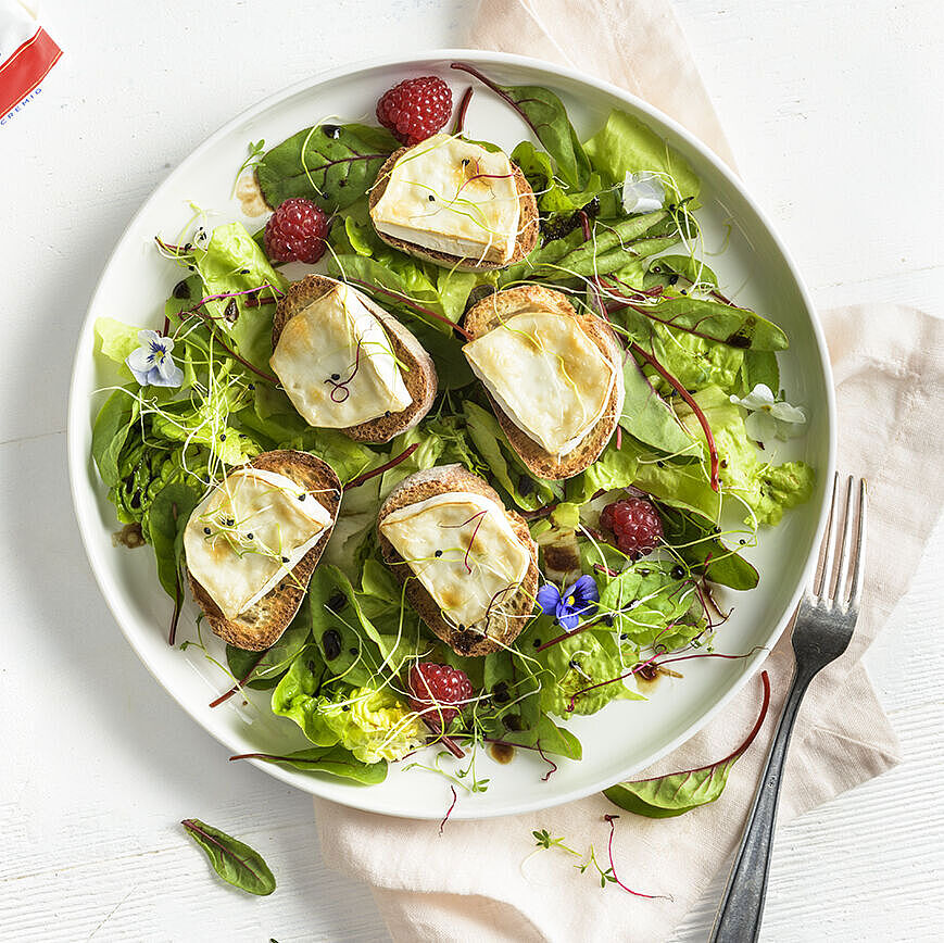 Salade de chèvre chaud sur un lit de roquette avec noix grillées, tranches de pommes et vinaigrette au miel.