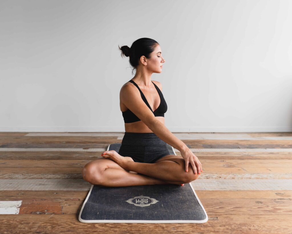 Une image d'une femme pratiquant une le yoga sur un tapis de yoga dans un salon.