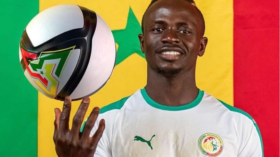 Sadio Mané portant le maillot tenant un ballon sur fond du drapeau sénégalais