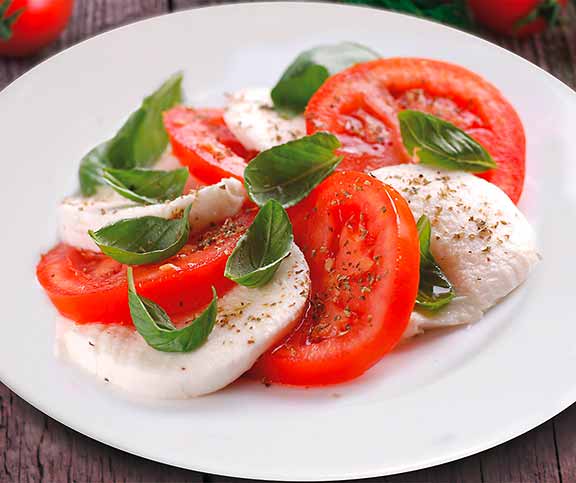 Salade de tomates et mozzarella avec tranches de tomates juteuses, mozzarella fraîche, basilic et vinaigrette balsamique